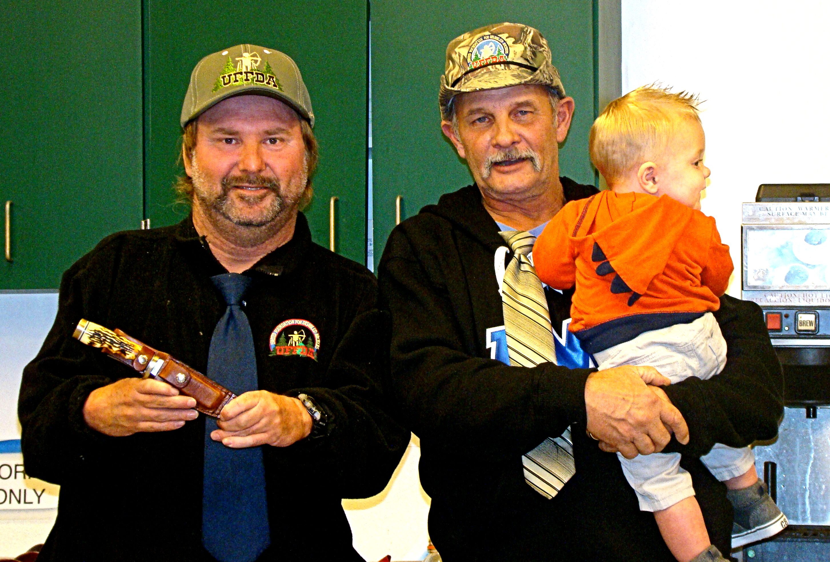 Head guide, complete with grandson in arms, Mark Skidmore presents Terry Schwartz with the Delaney's Sports Big Buck Award; an engraved Uncle Henry hunting knife donated by Kevin and Deb Lempola.